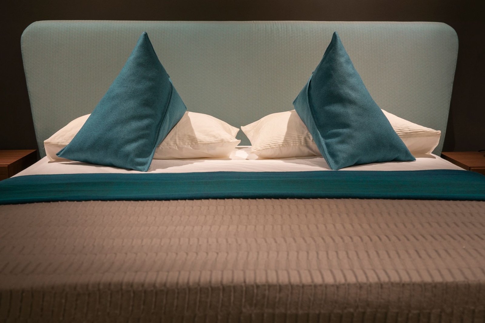 waterbed onderhoud — Modern minimalist bed with teal pillows and headboard, showcasing elegant interior design.