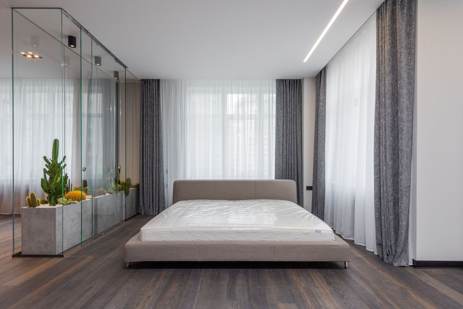 tijk voor waterbed — Interior of modern bedroom with comfortable bed and glasshouse with green plants which carrying out function of wall between areas in apartment