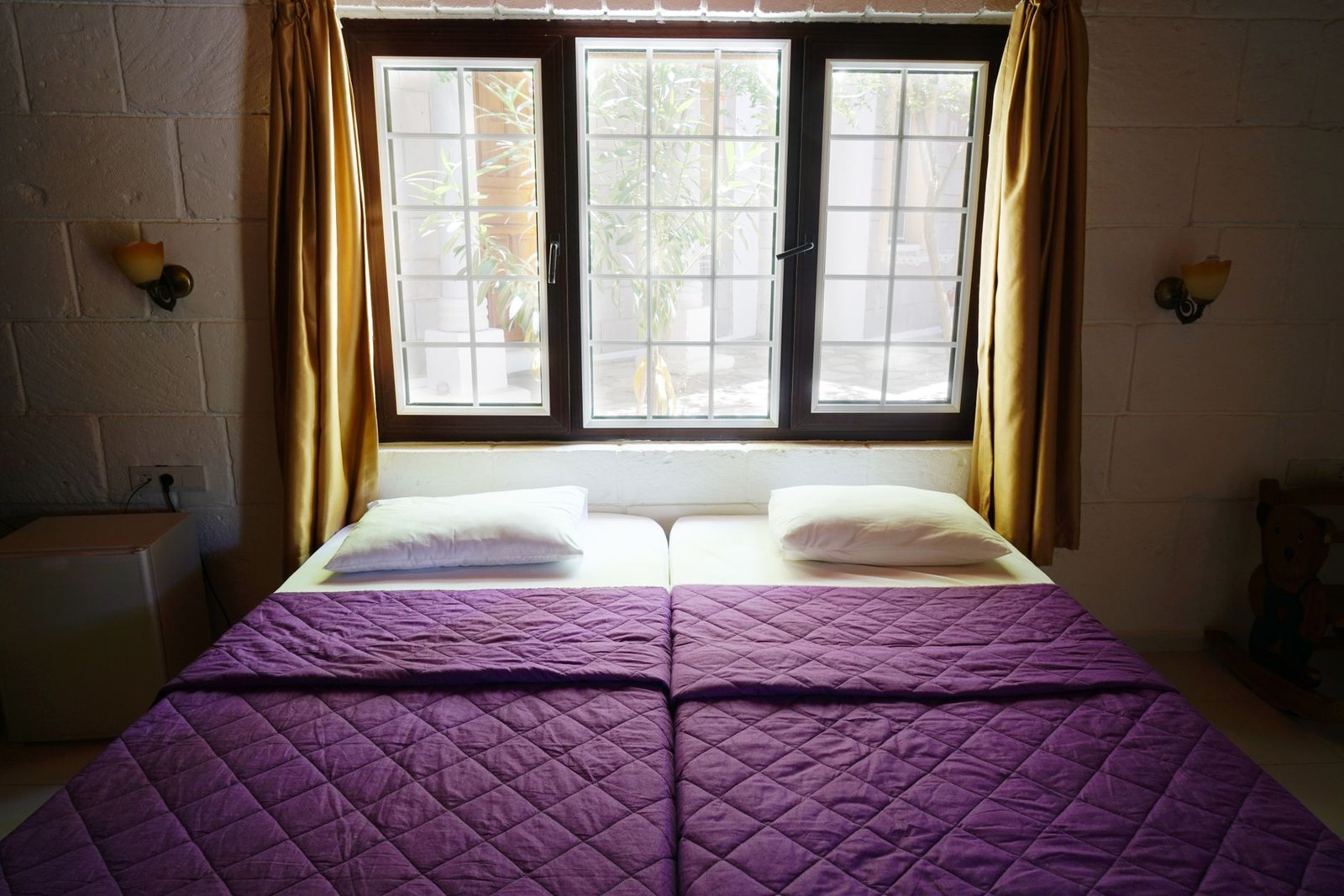 waterbed koel — Inviting bedroom featuring purple bedding, natural light through a window, and warm decor.