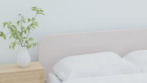 slaapsysteem — Soft and serene bedroom featuring white bedding and a vase with greenery on a wooden nightstand.
